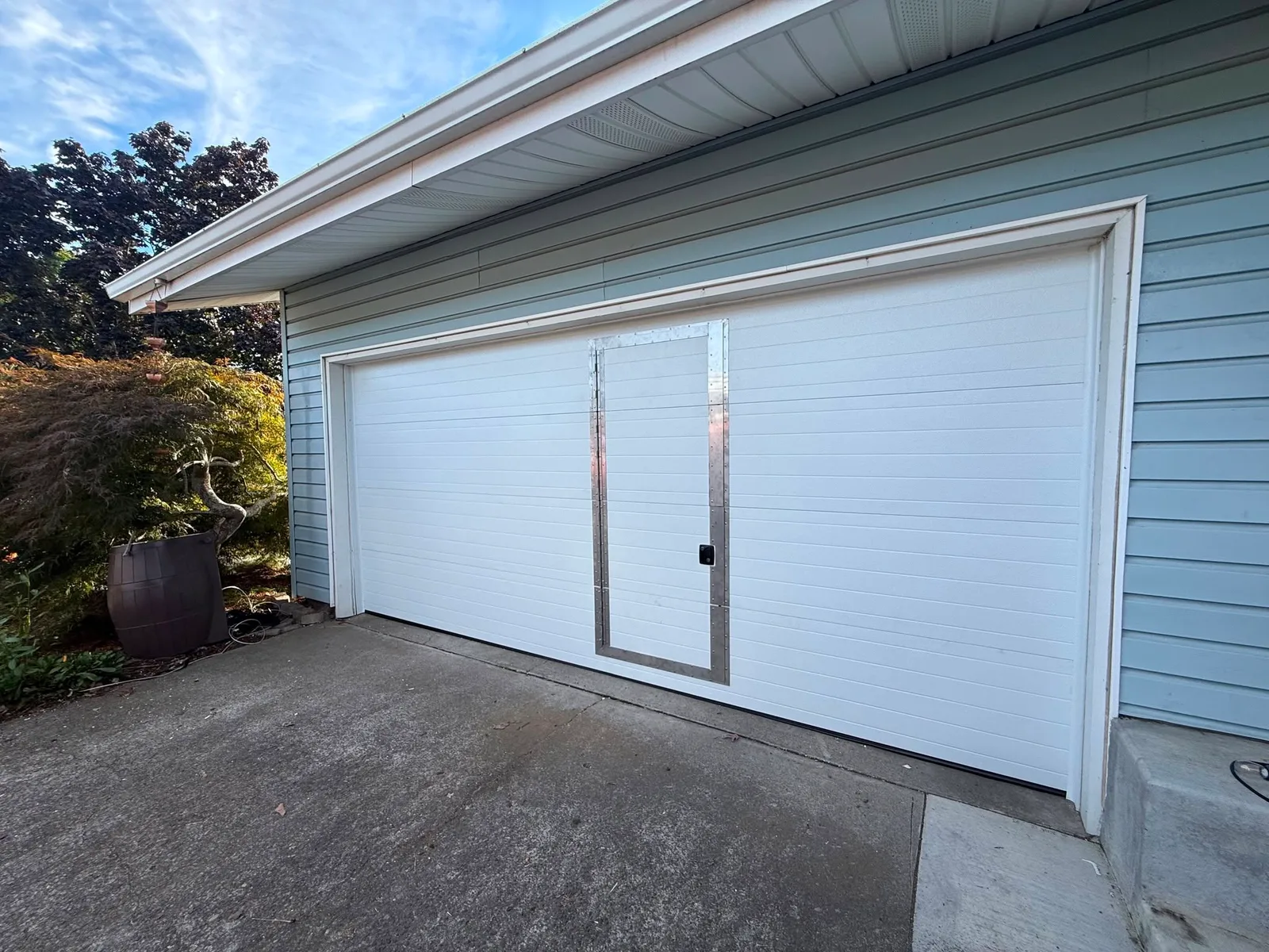 Closed exterior view of the completed white garage door and integrated pass door